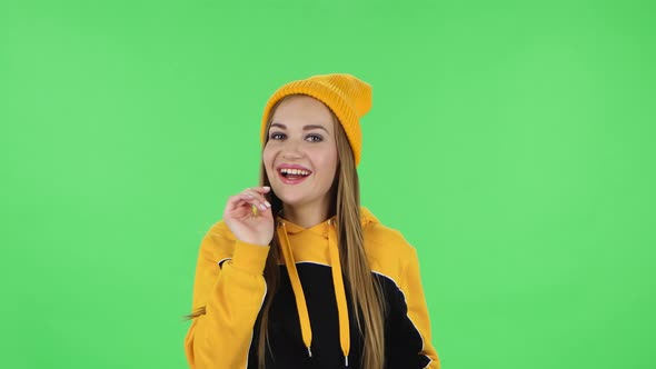 Portrait Modern Girl in Yellow Hat Is Girl Coquettishly Smiling, Waving Hand and Showing Gesture