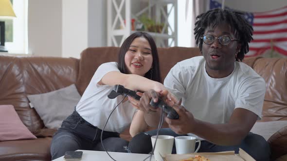 Cheerful Asian Girlfriend Cheating As African American Boyfriend Winning in Video Game Showing