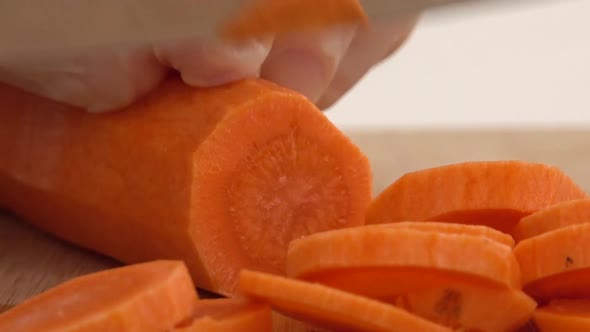 The cook cuts carrots on a cutting board.