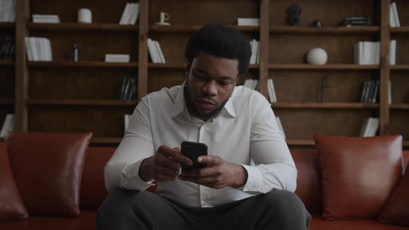 Young Adult Man Thinking and Nodding His Head in Front of His Smartphone