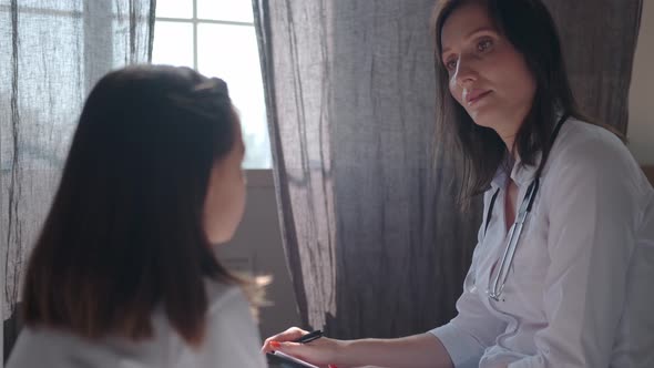 Attentive Female Doctor Examines the Girl and Asks Questions