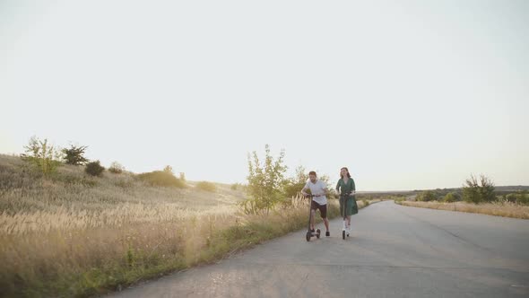 Young Couple in Love Riding Together on Electric Scooters with Joy on Road