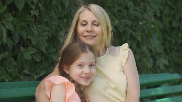 Portrait of Pretty Mature Blond Mother in Glasses and Her Little Daughter Looking at Camera While