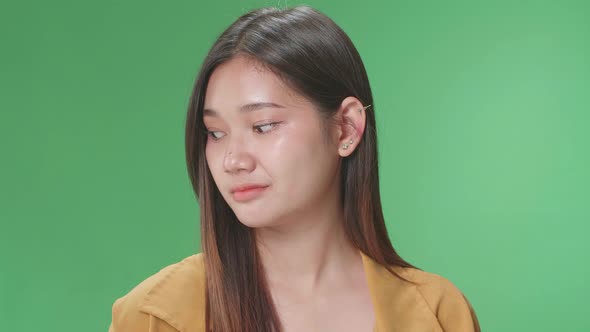 Young Asian Woman Emotionally Flipping Something While Standing In The Green Screen Studio