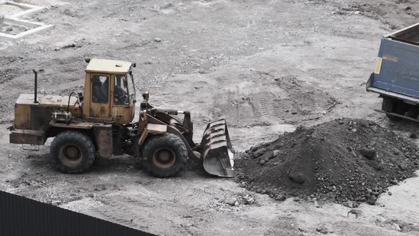 An Old Bulldozer on Rubber Wheels Works on Construction Site