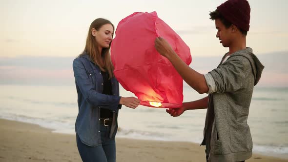 Young Multiethnic Couple Holding Red Paper Lantern Before Launching