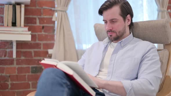 Casual Young Man Reading Book on Sofa