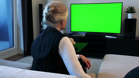 Old Caucasian Woman Watches Television in Living Room and She Is Angry