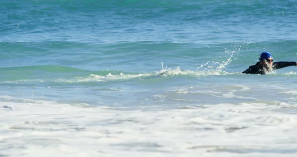 Male surfer swimming in the beach