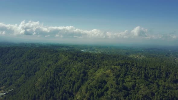 Fly Over a Mountain Forest. Beautiful Clouds Against the Blue Sky in the Horizon