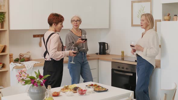 Three Adult Women Drinking Wine and Chatting in Kitchen