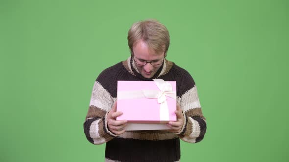 Studio Shot of Happy Handsome Man Opening Gift Box and Looking Surprised