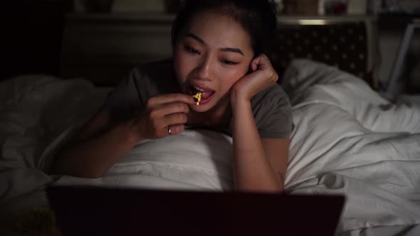 Asian woman lying in bed with laptop at night