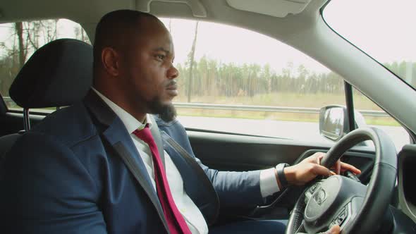 Side View of African Businessman Driving Car on Highway