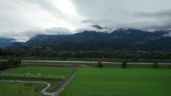 Liechtenstein with Houses on Green Fields in Alps Mountain Valley Aerial View