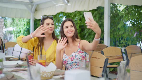 Young Women Have Lunch in Restaurant and Talking with Friend Online Via Video Calling on Smartphone