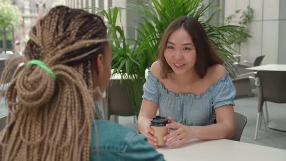 Two Female Friends Talking Over Coffee Outside a Coffee Shop