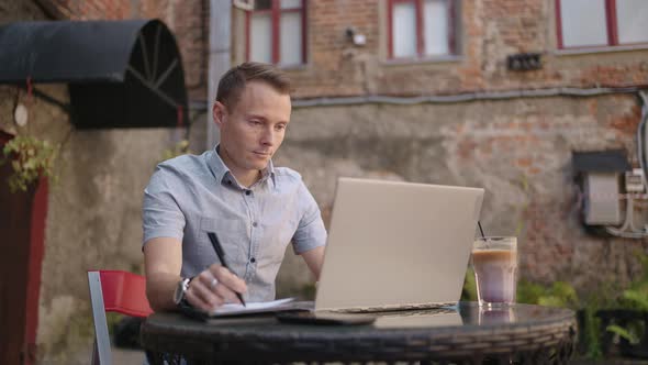 Smiling Man with Works From Home in His Kitchen Using a Laptop