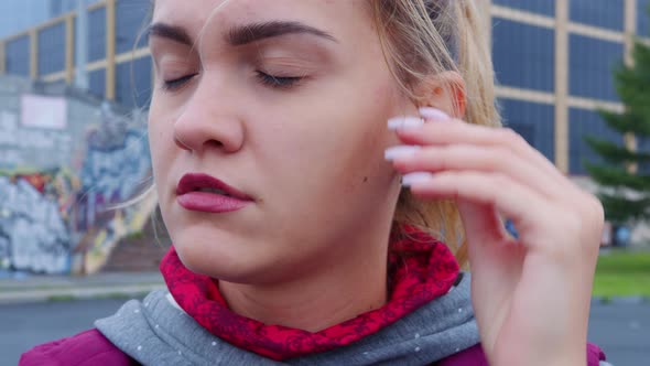 Girl Inserts Wireless Earphones Into Her Ears