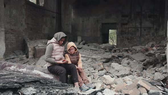 Little Girls Sitting on Ruins of Abandoned House