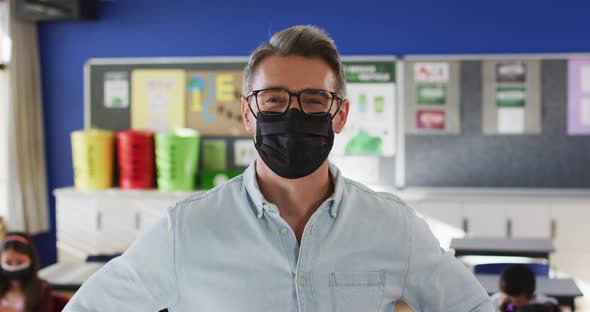 Portrait of caucasian male teacher wearing face mask in the class at school