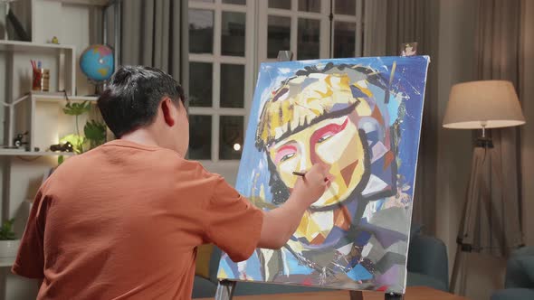 Asian Artist Boy Holding Paintbrush And Thinking Before Painting A Girl's Hair On The Canvas