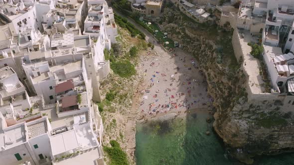 Aerial footage of Lama Monachile beach in Polignona a Mare, Italy with beachgoers relaxing.