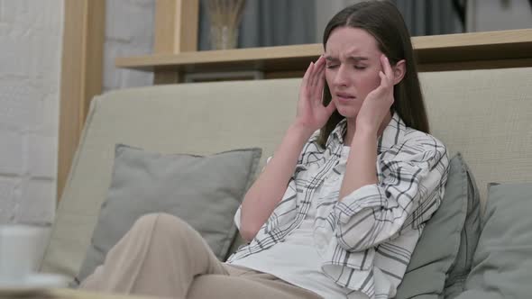 Beautiful Young Woman Sitting on Sofa and Having Headache