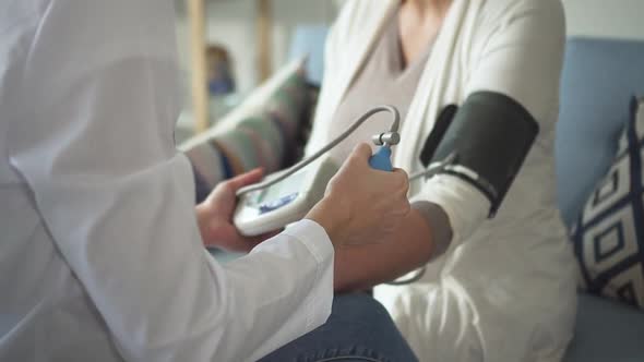 Doctor Is Taking Ultrasound Scan and Measuring Blood Pressure From Elderly Patient Using Scanning