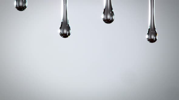 Super Slow Motion Macro Shot of Dripping Oily Liquid on Dark Grey Background at 1000 Fps alt