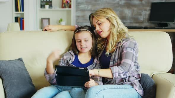 Beautiful Young Mother Using Tablet for Her Daughter Education