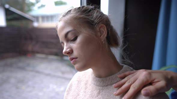 Depressed Teenage Girl Looking Out the Window As Female Hand Touching Shoulder