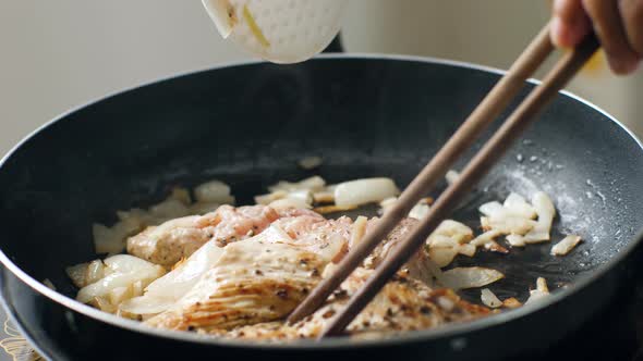 Close Up of Seasoned Chicken Breast Being Grilled in a Pan with Sauted Onions.