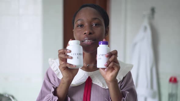 Positive African American Woman Advertising Vitamin E and D3 in Slow Motion in Bathroom