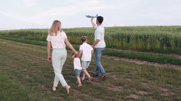 Family with Two Sons Is Walking Together in the Summer Field