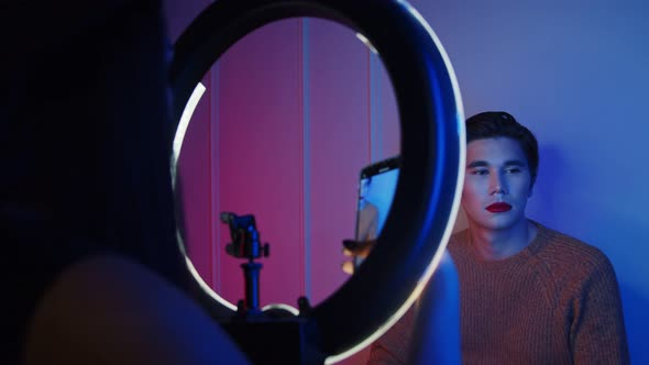 Makeup Studio - Woman Artist Taking Photo of Her Male Model with Makeup on in Neon Lighting Using