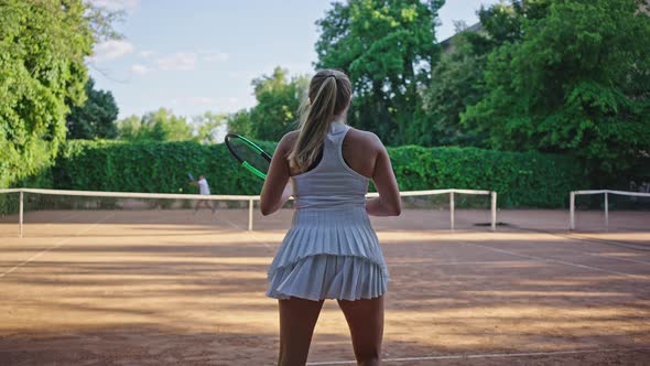 Female Tennis Player Plays Tennis with Man on Sand Court