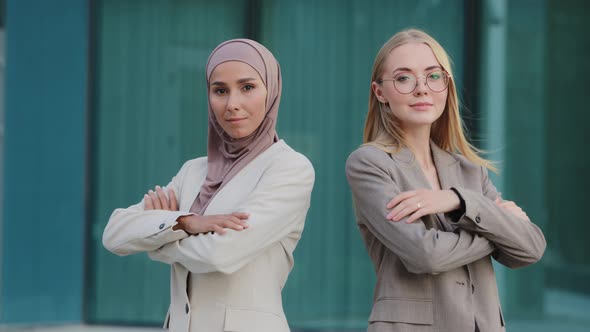 Confident Diverse Millennial Colleagues Indian Girl in Hijab and Young Caucasian Woman Wearing