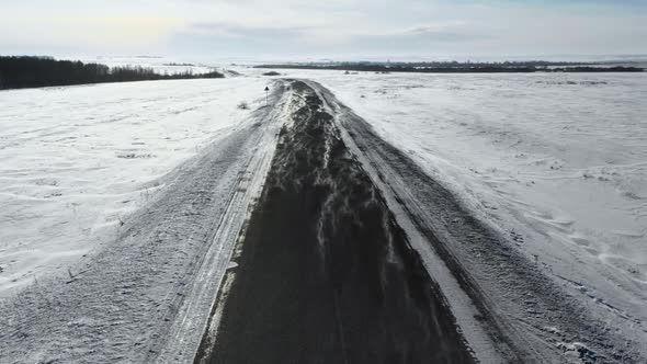 Flight at Low Altitude Over the Winter Road. Wind Overtakes the Snow Across the Road