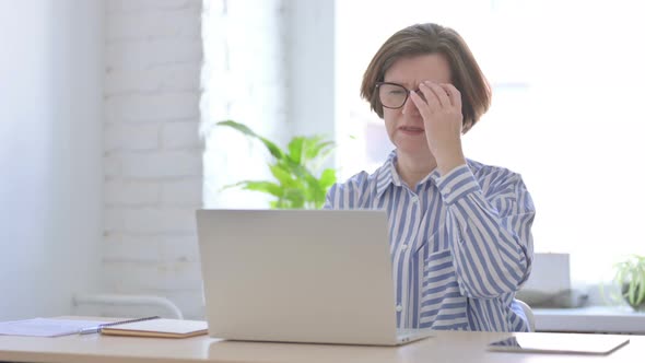 Tired Senior Woman Rubbing Eyes at Work