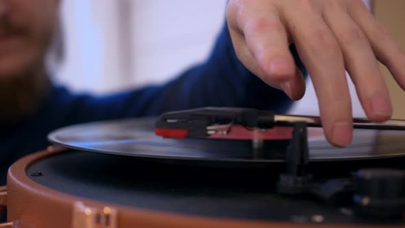 Closeup of a Man Putting a Vinyl Record Into a Turntable the Record Starts Spinning and a Needle is