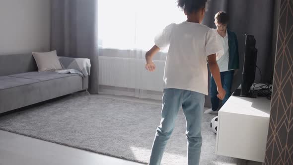 Children in Selfisolation Caucasian Boy and African Girl Playing with a Soccer Ball in the Living