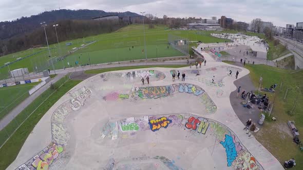 Aerial drone view of a young man riding a BMX bicycle in a concrete skate park covered in graffiti