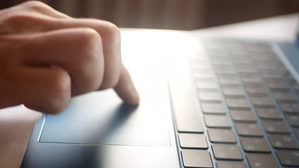 A Man Works on a Silver Laptop Using a Touchpad and Keyboard