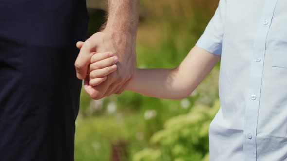 Close Up of Father and Little Son Holding Hands Outdoors