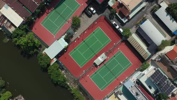 Aerial top down rotation of red and green tennis courts in a clockwise direction featuring small can