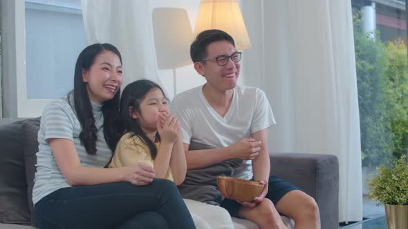 Lifestyle dad, mom and daughter watch TV together in living room in modern home .