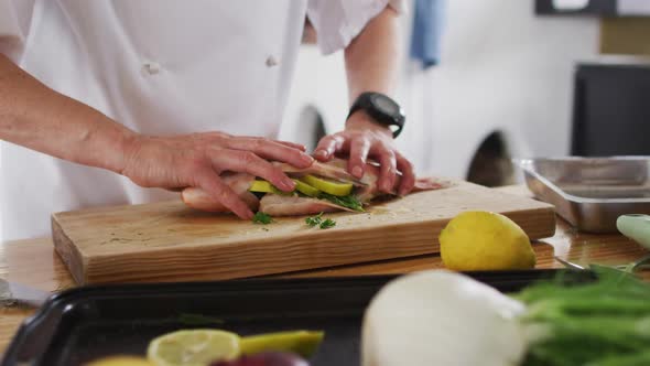 Caucasian female chef preparing a dish and smiling in a kitchen