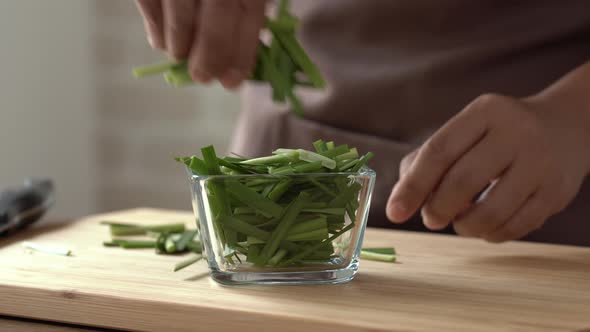 Green cut spring onion being put into glass blow