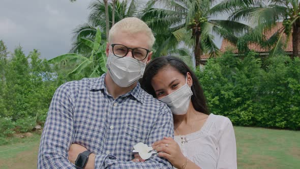 Portrait of an International Couple in Love a European Man and an Asian Woman Wearing a Face Mask